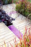 Decked path with pink tiles, planting of Heuchera 'Obsidian' and Imperata cylindrica 'Red Baron' - 'A Matter of Urgency', Silver Gilt medal winner - RHS Hampton Court Flower Show 2010 
 
 
