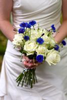 Bride holding a bouquet of white Roses and blue perennial Cornflower