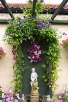 Clematis on trellis with classic stone water feature against painted garage wall. Manvers Street, Derbyshire NGS