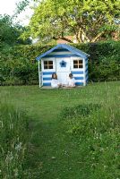 Children by the playhouse painted like a beach hut - Heveningham, Suffolk