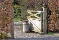 Open wooden gate with milk churn and Fagus sylvatica hedge in early Spring at Summerdale House, Cumbria
NGS