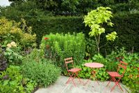 Hot border with colour co-ordinated furniture - Wilkins Pleck NGS, Whitmore, Staffordshire, UK. July 
