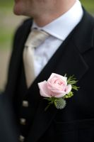 Pink rose buttonhole on a man with black jacket and tie