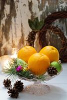 Christmas baubles, fir cones and oranges on a glass dish 