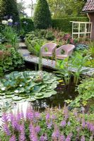 Pond with seating area, Astilbe chinensis 'Pumila' in foreground 