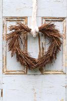 Christmas heart shaped wreath hanging on rustic door 
