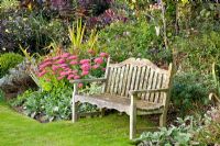 Wooden bench in country garden in late summer