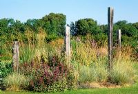 Wooden sculptures in a dry coastal garden with grasses and perennials