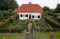 Overview of Dutch country garden. Buxus - Box parterre on left with Aster macrophyllus, Anemone 'Wirlwind', Sanquisorba, Nepeta faasennii and white Phlox. Parterre on right with Rosa 'Clair Matin'. Arch with Rosa 'Clair Matin' and Clematis jouiniana 'Praecox'. Schrijvershof, Holland 