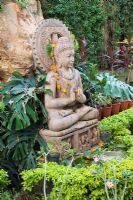 Spiritual chanting garden in India with stone Buddha, exotic plants including Monstera deliciosa 