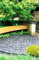 Wooden bench underplanted with ferns and Cornus contoversa 'Pagoda' in courtyard garden with stone paving setts - A Garden for Robin, designed by students at Leeds Metropolitan University 2006 RHS Chelsea Flower Show