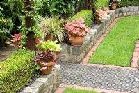 Paths and walls made from reclaimed cobbles, station platform tiles and bricks, and Buxus sempervirens - Box hedge, clay pots with Heuchera and trellis with Clematis - Brocklebank Road, Southport, Lancashire NGS 

