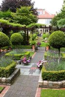 The secluded parterre garden with paths and walls made of small reclaimed cobbles, station platform tiles and bricks, parterre with Buxus sempervirens - Box hedges, Lavandula angustifolia 'Hidcote' and Thuja topiary standards, pergola with Clematis - Brocklebank Road, Southport, Lancashire NGS 
