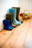 Four pairs of wellies of a gardening family in hallway with a wooden trug of Tulips