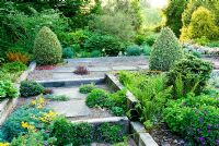 Shallow steps and raised beds constructed with weathered railway sleepers, plants seeded into the gravel path including Geraniums, Tropaeolum polyphyllum and Sempervivums - Ivy Croft, Leominster, Herefordshire, UK