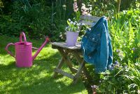 Picking Spring flowers with pink watering can in garden