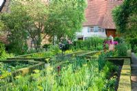 Cottage garden with vegetable garden containing Rosa 'Leonardo da Vinci', scarecrow, Buxus sempervirens and Calendula officinalis