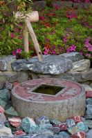 Water feature in a Japanese garden surrounded by Azalea japonica and Bamboo