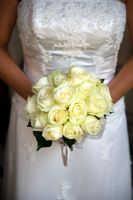 Bride holding a wedding bouquet of white or cream roses