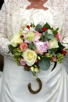 Woman in a wedding dress holding a brides bouquet of roses and peony
