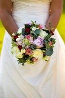 Woman in a wedding dress holding a brides bouquet of roses and peony