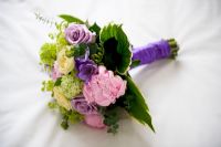 Bridal bouquet of cream and purple roses and pink peony with hosta leaves