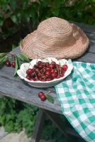 Bowl of cherries on table with sunhat