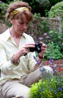 Lady in garden photographing flowers in pot