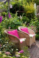 Small garden with wicker chairs surrounded by Digitalis - Foxgloves and Hydrangea - Scheper Town Garden
