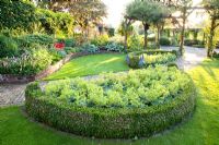 Garden with curved borders, pergolas and semi circular bed of Alchemilla mollis - Ladys Mantle with Buxus edging - Broekhuis Garden