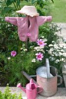 Scarecrow made with chlids pink cardigan in flower bed with Achillea and Cosmos