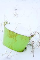 Lime green flexible garden bucket covered in snow winter