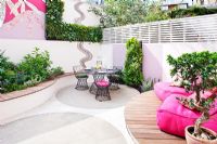 Small patio garden with decking, pink chairs, mosaic by Celia Gregory, London. 
