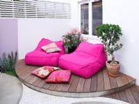 Raised decked patio with pink chairs and floral patterned cushions, London. 
