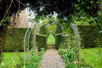 Formal cobble path and rose arch with tulips