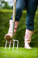 Woman digging lawn with stainless steel garden fork
