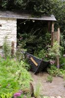 Wooden boat used as planter in rustic outbuilding 