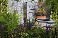 A vertical water feature set in a slate wall with a seating area 