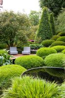Patio under tree surrounded by mounds of clipped Buxus - Box, Hakonechloa macra, Carpinus betulus - Hornbeam, Betula and Arum Lily in 'The Irish Sky Garden' - Gold Medal Winner, RHS Chelsea Flower Show 2011

