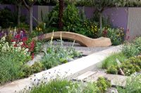 Seating area with curved timber bench and salt tolerant planting including Armeria - Thrift, and Centranthus ruber - The Cancer Research UK Garden, Silver Gilt Medal Winner, RHS Chelsea Flower Show 2011 