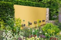Colourful summer borders backed by Taxus - Yew hedging and yellow painted feature wall with water pipes. 'The Daily Telegraph Garden', Gold Medal Winner and Best in Show - RHS Chelsea Flower Show 2011 
