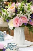 Flower arrangement in white ceramic jug, flowers include pink and white Rosa, Astrantia, Antirrhinum and Veronicastrum
