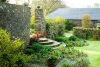 Semi-circular steps lead from formal lawn down into sunken summer garden, with wall trained apple tree to one side