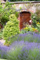 View across lavender border to the wooden door in brick wall, The Round House