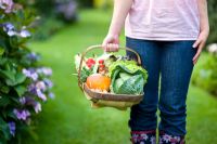 woman holding a wooden trug of autumn vegetables 