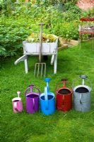 Different coloured watering cans in vegetable garden
