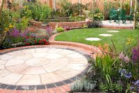 Small back garden with colourful borders, circular patios with seating, lawn with stepping stones and raised brick pool by Mook Garden Design - Southport Flower Show 2011