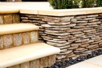 Sandstone steps and paving next to low dry stone wall

