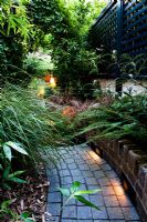 Pathway through illuminated raised beds in secluded suburban garden at dusk 