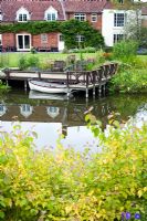 Natural pond with small jetty and boat, late summer planting - Dales Farm, Norfolk NGS
